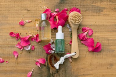 Spa doğal tedavi fikri: ahşap fırça ve doğal bir ahşap zemin üzerinde iki güzellik ürünü şişesi
