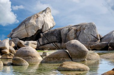 Mavi bulutlu gökyüzünün arka planında büyük granit kayalardan oluşan tuhaf bir karmaşa..