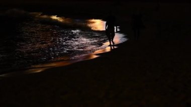 Fransa, Cannes 'da gece denizde yürüyen bir çift.