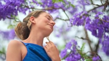 Mavi elbiseli beyaz kadın, Barselona, İspanya 'da pembe çiçekli ağaç.