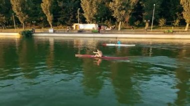 CHISINAU, MOLDOVA - 4 Eylül 2021: günbatımında Valea Morilor parkının hava aracı görüntüsü. Yeşillik, göl, iki adam kayak yapıyor.