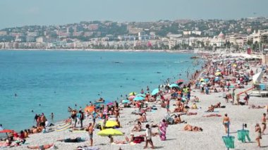 Güzel, FRANCE - 8 Ağustos 2021: cote d 'Azur manzarası. Sahilde dinlenen insanlar, binalar, Akdeniz 'in mavi suları.