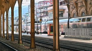 GÜZEL, FRANCE - 21 AĞUSTOS 2021: İnsanlı tren istasyonu ve hareket halindeki tren manzarası