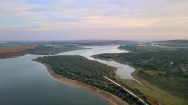 Moldova 'daki Duruitoarea doğal rezervasyonunun hava aracı görüntüsü. Nehir ve sis havada, tepeler ve tarlalar, yolları ve yeşillikleri olan köy.