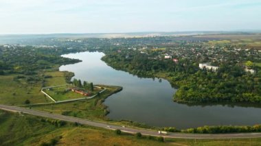 Moldova 'daki bir kasabanın insansız hava aracı görüntüsü. Konut binaları, hareket halindeki arabalar, yeşillik, göl...