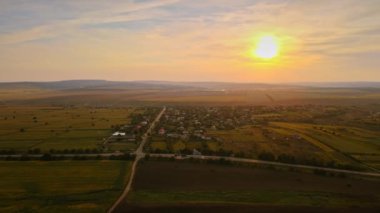 Gün batımında Moldova 'daki köyün insansız hava aracı görüntüsü. Yerleşim yerleri, yeşillikler, hareket halindeki arabalı yollar, geniş alanlar.