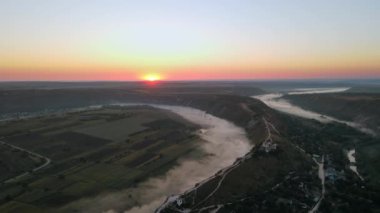 Gün batımında Eski Orhei 'nin hava aracı görüntüsü. Nehir ve sisli vadi, köy ve manastır Moldova 'da bir tepenin üzerinde yer alıyor.