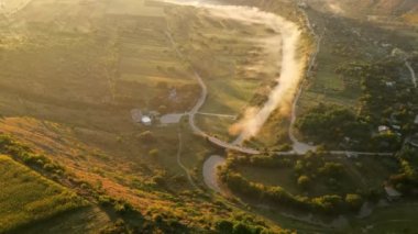 Gün batımında Eski Orhei 'nin hava aracı görüntüsü. Nehir ve sisli vadi, köy ve manastır Moldova 'da bir tepenin üzerinde yer alıyor.