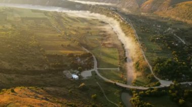 Gün batımında Eski Orhei 'nin hava aracı görüntüsü. Nehir ve sisli vadi, köy ve manastır Moldova 'da bir tepenin üzerinde yer alıyor.