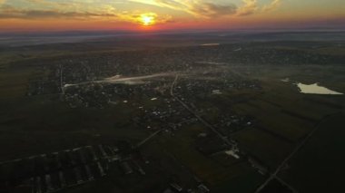 Gün batımında Moldova 'daki köyün insansız hava aracı görüntüsü. Yangınlardan ve geniş alanlardan dumanlar yükseliyor.