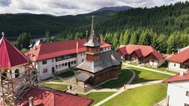 Romanya 'daki Oasa Manastırı' nın insansız hava aracı görüntüsü. Kiliseler, ziyaretçiler, Karpat Dağları, ormanlarla kaplı tepeler