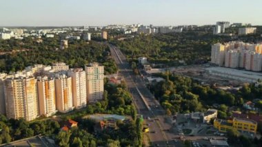 Chisinau 'nun günbatımında hava aracı görüntüsü. Birden fazla bina, yol ve arabalı köprü. Yeşillikle park et.