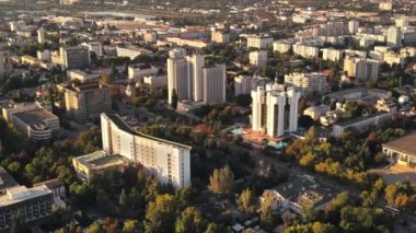 Chisinau 'nun gün batımında hava aracı görüntüsü. Birden fazla binanın manzarası, Parlamento, Başkanlık, hareketli arabalı yollar ve gür ağaçlar. Moldova