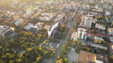 Chisinau 'nun gün batımında hava aracı görüntüsü. Birden fazla binanın manzarası, Parlamento, Başkanlık, hareketli arabalı yollar ve gür ağaçlar. Moldova