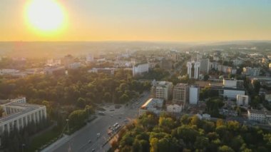 Chisinau 'nun gün batımında hava aracı görüntüsü. Birden fazla binanın manzarası, Parlamento, Başkanlık, hareketli arabalı yollar ve gür ağaçlar. Moldova
