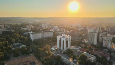 Chisinau 'nun gün batımında hava aracı görüntüsü. Birden fazla binanın manzarası, Parlamento, Başkanlık, hareketli arabalı yollar ve gür ağaçlar. Moldova