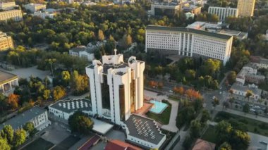 Chisinau 'nun gün batımında hava aracı görüntüsü. Parlamento manzarası, başkanlık, hareket halindeki arabalar ve yemyeşil ağaçlar. Moldova