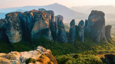 Meteora 'nın günbatımında Yunanistan' daki hava aracı görüntüsü. İnsanlarla dolu kaya oluşumları. Bir sürü yeşillik, kutsal bir yer