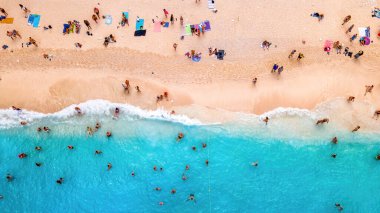 Yunanistan 'ın Zakynthos kentindeki İyon Denizi kıyısındaki Navagio plajının insansız hava aracı görüntüsü. Dinlenen insanlar, mavi su