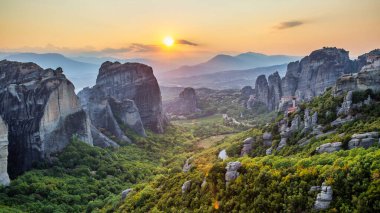 Meteora 'nın günbatımında Yunanistan' daki hava aracı görüntüsü. Ortodoks manastırlı kaya oluşumları. Bir sürü yeşillik, kutsal bir yer