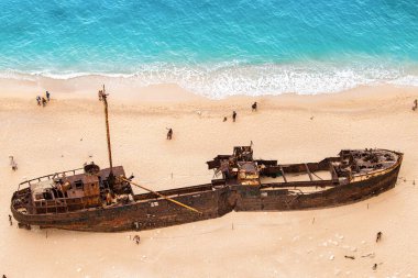 İyon Denizi kıyısındaki Navagio sahilinin insansız hava aracı görüntüsü. Paslı bir geminin yanında dinlenen insanlar, Yunanistan 'ın Zakynthos kentindeki mavi su