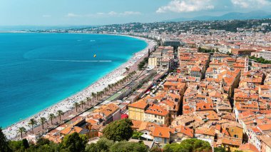 Nice, Fransa 'daki Cote d' Azur manzarası. Sahilde dinlenen insanlar, binalar, Akdeniz 'in mavi suları, arka planda tepeler.