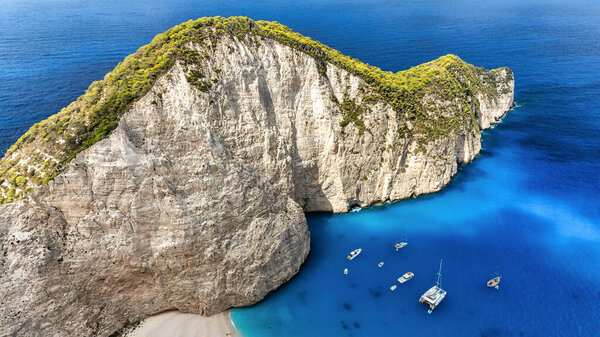 Вид с воздуха на пляж Наваджио на побережье Ионического моря Закинфа, Греция. Скалистые скалы, пришвартованные лодки, голубая вода