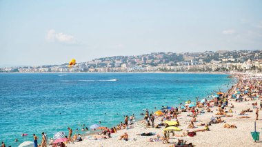 Güzel, FRANCE - 8 Ağustos 2021: cote d 'Azur manzarası. Sahilde dinlenen insanlar, binalar, Akdeniz 'in mavi suları.