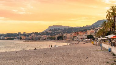 Gün batımında, Menton, Fransa 'daki Cote d' Azur manzarası. Sahilde çok az insan, binalar, Akdeniz suları...