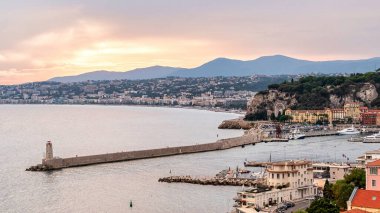 Nice, Fransa 'da gün batımında deniz limanı manzarası. Bağlı tekneler ve yatlar, binalar ve yeşillikler