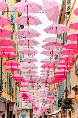 GRASSE, FRANCE - 3 Eylül 2021: şehrin sokak manzarası. Pembe şemsiyeli dar sokaklar