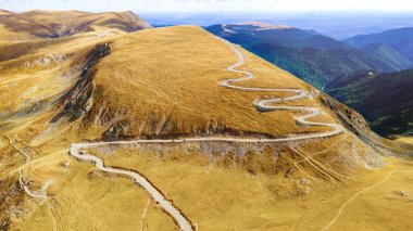 Romanya 'da doğanın insansız hava aracı görüntüsü. Karpat dağları, bitki örtüsü, yeşillikli vadi, arabalı yol