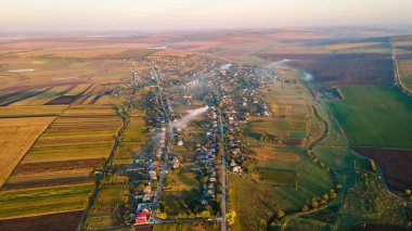 Gün batımında Moldova 'daki köyün insansız hava aracı görüntüsü. Yangınlardan ve geniş alanlardan dumanlar yükseliyor.