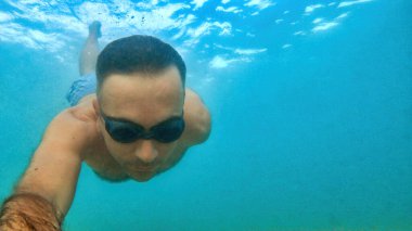 Gözlüklü adam Akdeniz 'in mavi ve şeffaf sularında yüzüyor. Kamerayı tutuyorum.