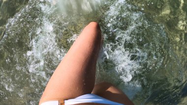 Akdeniz 'in sularında yürüyen beyaz mayo giymiş bir kadın. Bakış açısı