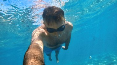 Gözlüklü adam Akdeniz 'in mavi ve şeffaf sularında yüzüyor. Kamerayı tutuyorum.