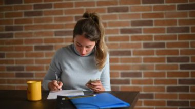 Cep telefonuyla çalışan ve ofiste yazan bir kadın.