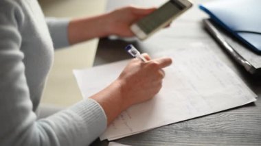 Cep telefonuyla çalışan ve ofiste yazan bir kadın.