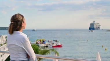 Fransa, Cannes 'da gemileri ve deniz feneriyle Akdeniz kıyılarını izleyen bir kadının arka görüntüsü.