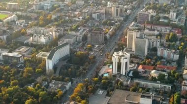 Chisinau 'nun gün batımında hava aracı görüntüsü. Birden fazla binanın manzarası, Parlamento, Başkanlık, hareketli arabalı yollar ve gür ağaçlar. Moldova