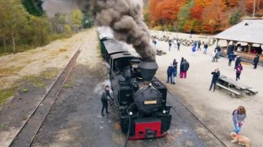 VISEU DE SUS, ROMANIA - 29 Ekim 2021: Buharlı Mocanita treninin hava aracı görüntüsü ve tren istasyonunda bir sürü turist
