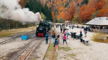 VISEU DE SUS, ROMANIA - 29 Ekim 2021: Buharlı Mocanita treninin hava aracı görüntüsü ve tren istasyonunda bir sürü turist
