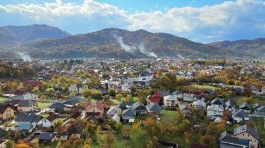Romanya 'nın Viseu de Sus kentindeki hava aracı görüntüsü. Bir sürü ev, kilise, tepeler sararmış ormanlarla kaplı.