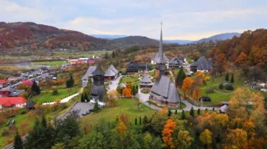 Romanya 'daki Barsana Manastırı' nın hava aracı görüntüsü. Ana kilise ve diğer binalar, ziyaretçiler, tepeler sararmış ormanlarla kaplı.