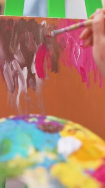 Stüdyoda palet ve fırça kullanarak resim yapan bir kadın.