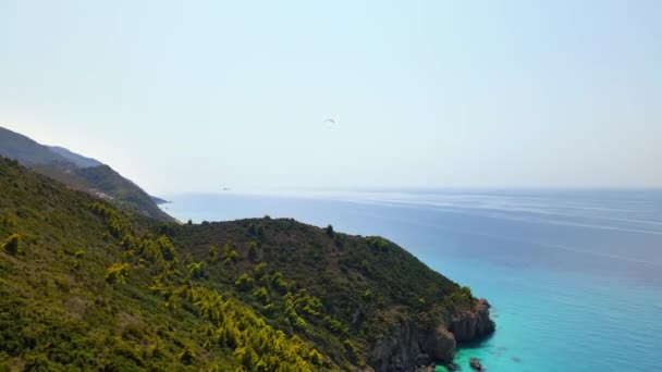 从空中俯瞰希腊Zakynthos的爱奥尼亚海海岸 山上绿油油的 人在降落伞上盘旋 蓝色的水 — 图库视频影像
