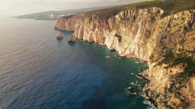Yunanistan 'ın Zakynthos kentindeki İyon Denizi kıyılarının insansız hava aracı görüntüsü. Kayalık kayalıklar, bitki örtüsü, mavi su. Gün batımı