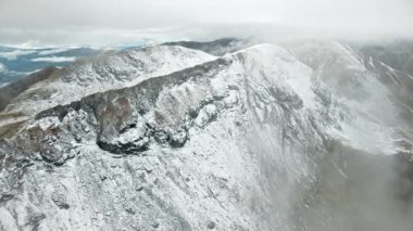 Romanya 'da doğanın insansız hava aracı görüntüsü. Karpat dağlarında transfagarasan rotası, dağlarda kar kayalık yamaçlar, bulutlar