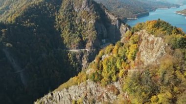 Romanya 'da doğanın insansız hava aracı görüntüsü. Vidraru barajı ve gölü olan Karpat dağlarındaki vadi, yemyeşil ormanlı yamaçlar.