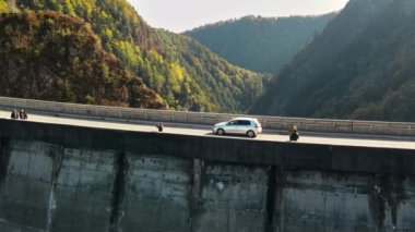 Romanya 'da doğanın insansız hava aracı görüntüsü. Carpathian dağlarında Vidraru barajı olan bir vadi, insanlar ve hareket halindeki arabalar, yemyeşil ormanlı yamaçlar